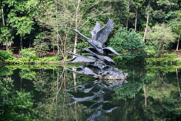 Statue of swans and its reflection in the lake at Singapore's Botanical Garden