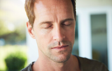 Fototapeta premium Man, serious and eyes closed with relax outdoor for meditation, mindfulness and spiritual wellness in morning. Person, calm and zen with resting in home for fresh air, peaceful and mental health