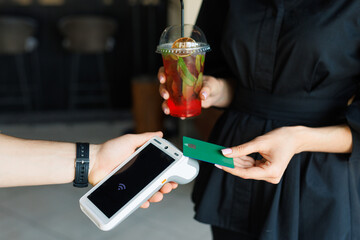 NFC credit card payment. Woman paying with contactless credit card with NFC technology. Wireless money transaction. Card machine in male hand on sunlight background