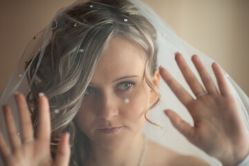 Fototapeta premium Morning of the bride in a white dress and elegant hairstyle. Young attractive, happy girl posing at home. Happiness, purpose and dream wedding.