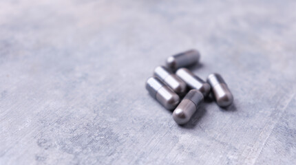 Amino acids capsules on bright stone background. Soft focus. Close up. Copy space.	