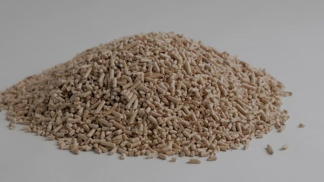 pile of wood pellets for heating with human hand white background slow motion