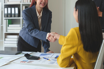 Two confident businesswomen holding hands during office meeting. Success. Executives. Coworkers standing and applauding. Congratulations teamwork concept.