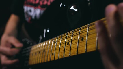 Close-up of strings and hands of a musician skilfully playing riffs on a light maple electric guitar fingerboard. Slow motion. Honing the skills of playing the guitar