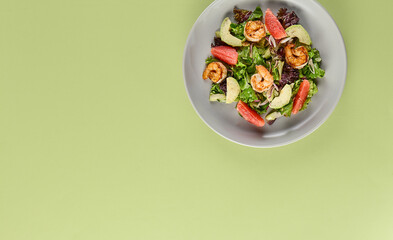 Fresh Shrimp Salad with Avocado and Grapefruit on Light Green Background