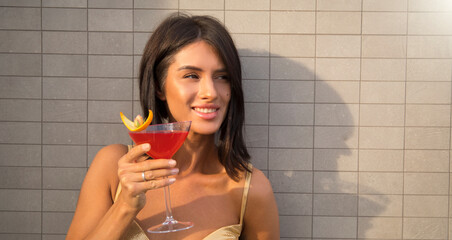 Happy woman in bikini and sunglasses holding cocktail, having fun 