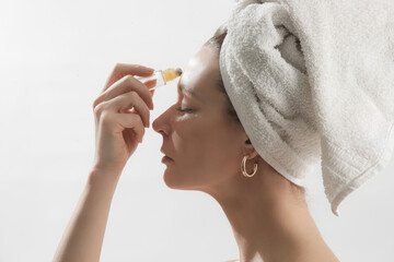 Studio shot of woman applying healing essential oil roller blend. Organic aromatherapy scent, all...