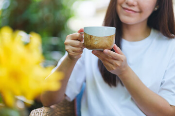Closeup image of a young woman holding and drinking coffee
