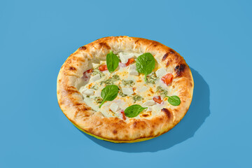 Four cheese pizza with tomatoes and spinach on a bright blue background. Minimalist style, side view. Perfect for a modern food photography, takeout or casual meal