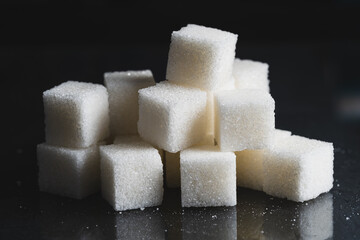 Pile of refined sugar cubes dark background.