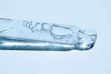 Pipette with body and face gel on a blue background with bright light, front view.