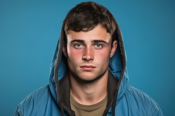 Fototapeta premium A young man wearing a blue hoodie and a brown shirt is looking at the camera