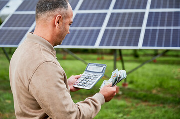 Confident investor counting profit he got from investing in green energy. Glad man holding huge sum...