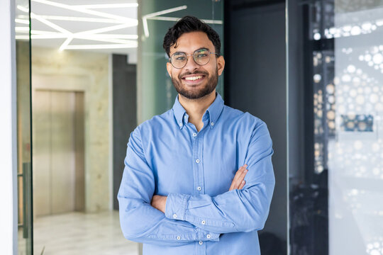 Confident young professional standing in modern office with arms crossed