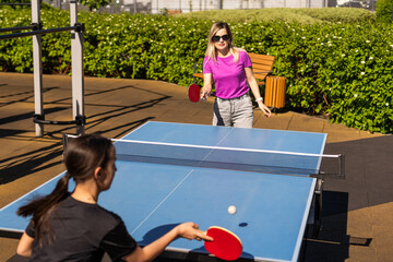 Happy mother and daughter play ping pong