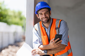 A chief engineer in a hard hat walks through modern factory lighting while holding a laptop. Successful handsome man in a modern industrial environment.