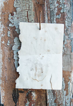 Old vintage paper advertisement hanging on aged wall nailed by rusty doornail