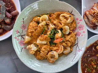 Omelette with shrimp and seafood on rice and sauce on white ceramic plate and spoon and fork.