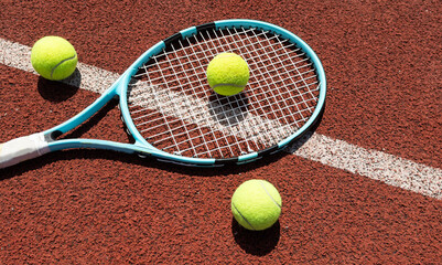 Racket with a tennis ball on a red clay court.