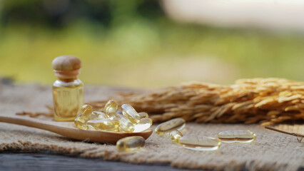 Capsule rice barn oil in wooden spoon with cold press rice barn oil. Rich in good fats, vitamin E,...