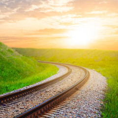 rail road turn  among green fields at the sunset