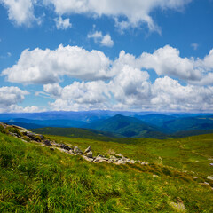 wide green mountain valley under a blue cloudy sky