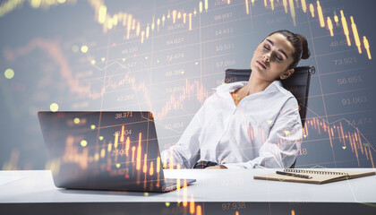 Attractive sleepy young businesswoman at desk with laptop, supplies and downward red forex...
