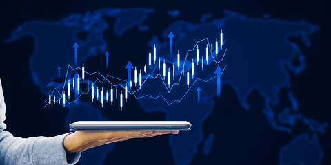 Close up of female hand holding tablet with growing forex chart with arrow and map on dark...