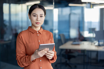 Confident businesswoman using digital tablet in modern office space, conveying professionalism and focus in a corporate setting.