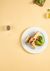 Grilled beef shawarma on a white plate with fresh lettuce and tomatoes, displayed on a warm yellow background with top view and copy space