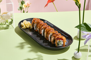 Stylish sushi setup with seared tuna roll, cucumber, and spicy sauce on a minimalist floral background