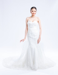Fototapeta premium Asian young beautiful female portrait attractive model of bride wearing fashion wedding dress, luxury delight make-up, hairstyle, standing looking camera isolated white background studio indoor photo