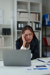 Fototapeta premium A businesswoman who is tired, stressed, and sore from working for a long time. After waiting for news Unsuccessful business approval results on laptop in office. Startup time concept, office syndrome