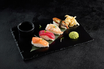 Classic nigiri sushi with salmon, tuna, eel, and shrimp on a black slate