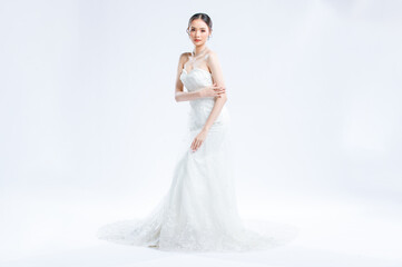 Asian young beautiful female portrait attractive model of bride wearing fashion wedding dress, luxury delight make-up, hairstyle, standing looking camera isolated white background studio indoor photo