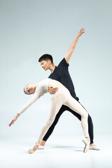 Modern Ballet Ideas. Professional International Sportive Couple of Asian Man and Caucasian Woman Performing As Ballet Dancers On Grey in Studio During Suppots As Classical Dance © danmorgan12