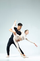 Modern Ballet Ideas. Sensual Passionate Professional International Sportive Couple of Asian Man and Caucasian Woman Performing As Ballet Dancers On Grey in Studio During Suppots As Classical Dance © danmorgan12