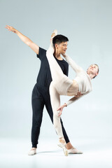 Modern Ballet Ideas. Sensual Passionate Professional International Sportive Couple of Asian Man and Caucasian Woman Performing As Ballet Dancers On Grey in Studio During Suppots © danmorgan12