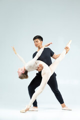 Dancing Ideas and Concepts. Sensual Passionate Professional International Sportive Couple of Asian Man and Caucasian Woman Performing As Ballet Dancers On Grey in Studio During Suppots © danmorgan12