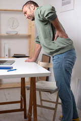 Man with back pain while working on a laptop.