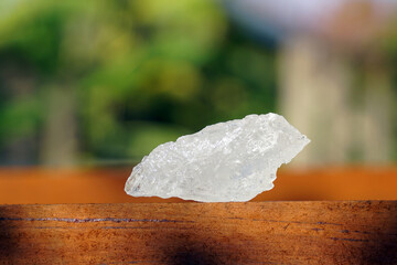 Lumps of alum on wood background. It is a mineral with clear, white crystals, odorless, astringent taste, ground into a white powder that resembles rock sugar.