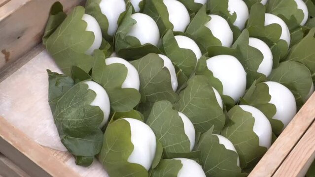 Hand picking selling rice ball moji traditional rice cake with leaf in Japanese market sweet dessert