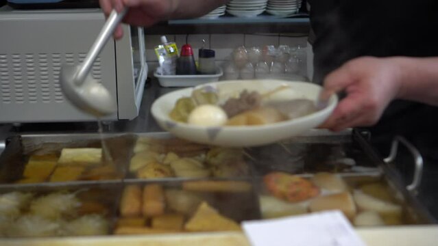 Oden restaurant serving steamed daikon fishcake meat and soup hot boiled food for cold Autumn winter 4k