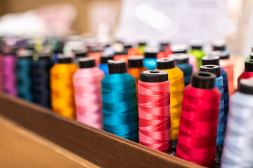 Selective focus to colorful sewing threads in a sewing shop. Repair or correction of clothing sizes.