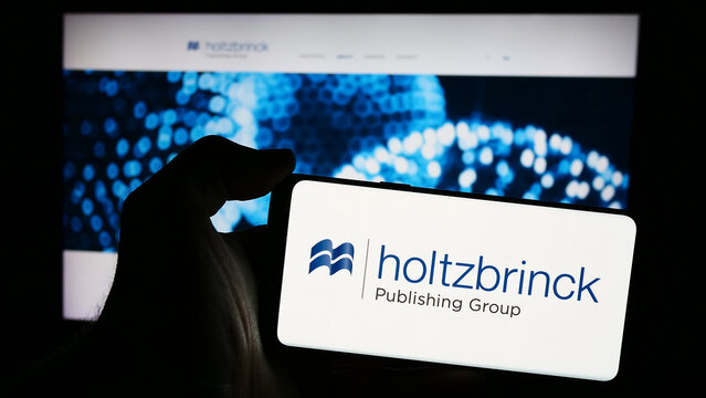 Stuttgart, Germany - 05-22-2024: Person holding mobile phone with logo of German media company Holtzbrinck Publishing Group in front of business web page. Focus on phone display.