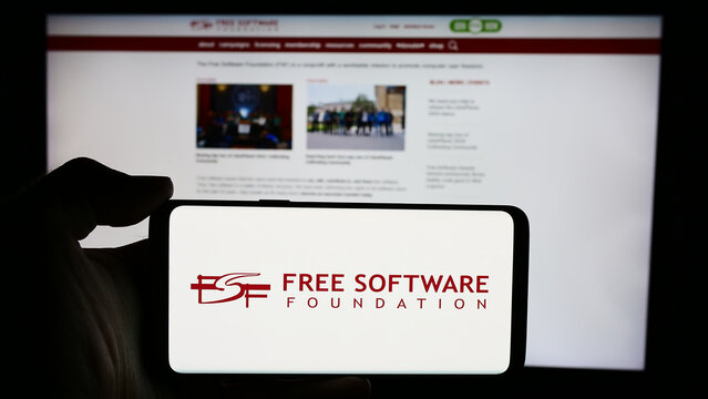 Stuttgart, Germany - 05-22-2024: Person holding cellphone with logo of US organisation Free Software Foundation (FSF) in front of webpage. Focus on phone display.