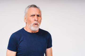Amazed gray-haired bearded man posing in studio, looking at camera isolated on white