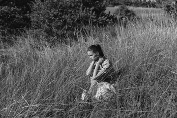 Woman relaxing in tall grass near forested area in black and white photography beauty of nature and...