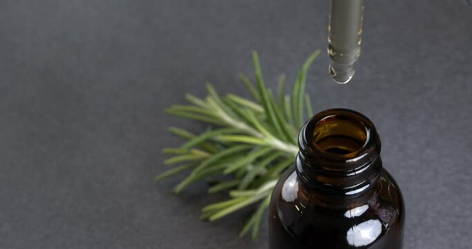 Cosmetic dropper with essential oil dripping into a bottle. 4K close-up video.