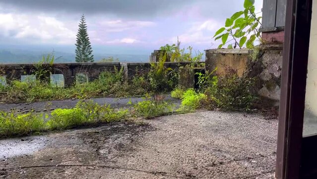 View from the room to the balcony terrace overgrown with grass and trees in haunted palace of the abandoned hotel resort in Pondok Indah Bedugul, Bali Indonesia. High quality FullHD footage